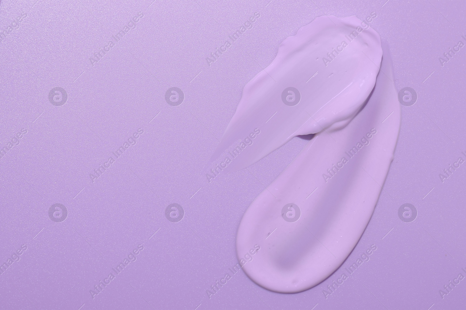 Image of Samples of face cream on violet background, top view. Space for text