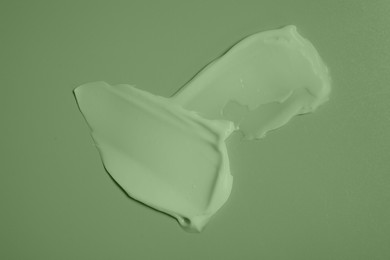 Image of Samples of face cream on green background, top view