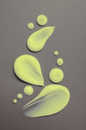 Image of Samples of yellow face cream on grey background, flat lay