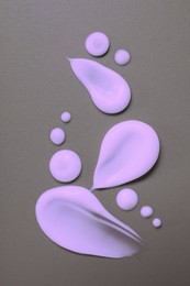 Image of Samples of violet face cream on grey background, flat lay