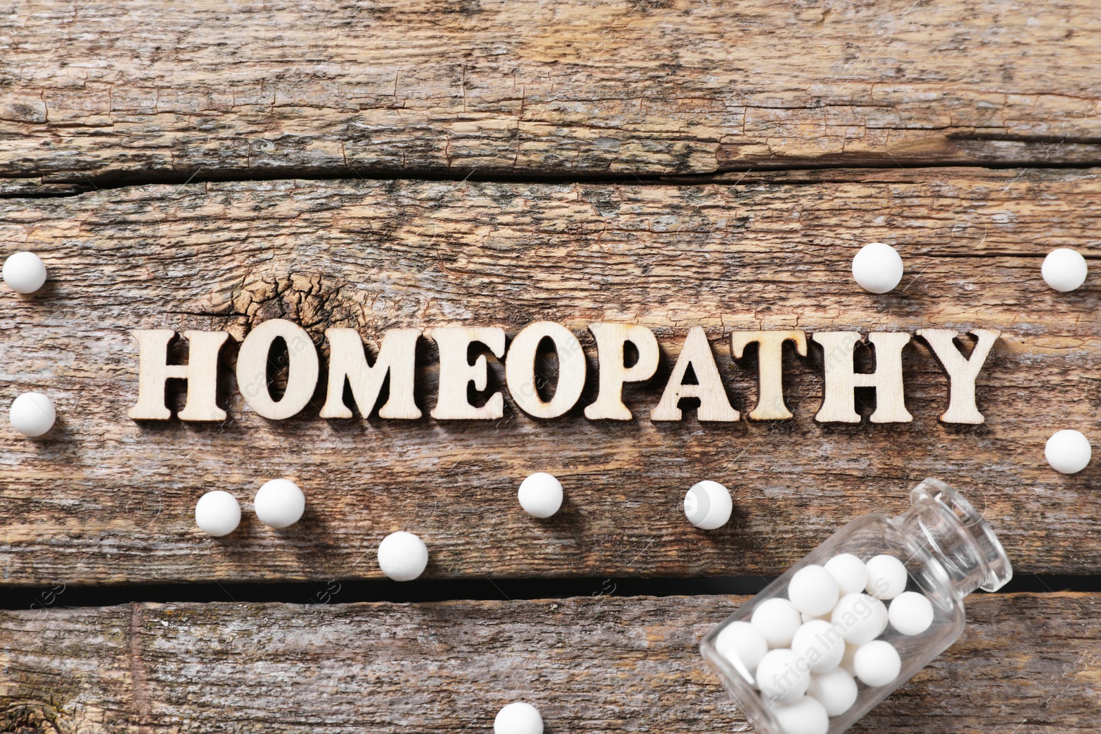 Photo of Word Homeopathy and pills on wooden background, flat lay