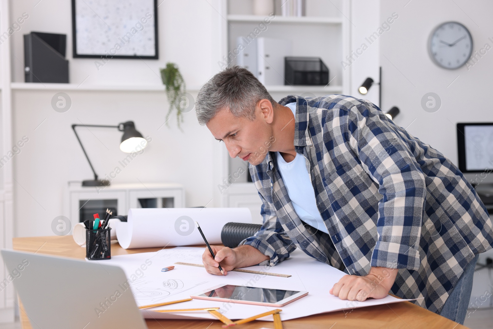 Photo of Architect making engineering drawing at wooden table in office