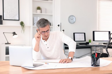 Architect making engineering drawing at wooden table in office