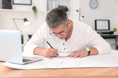 Architect making engineering drawing at wooden table in office