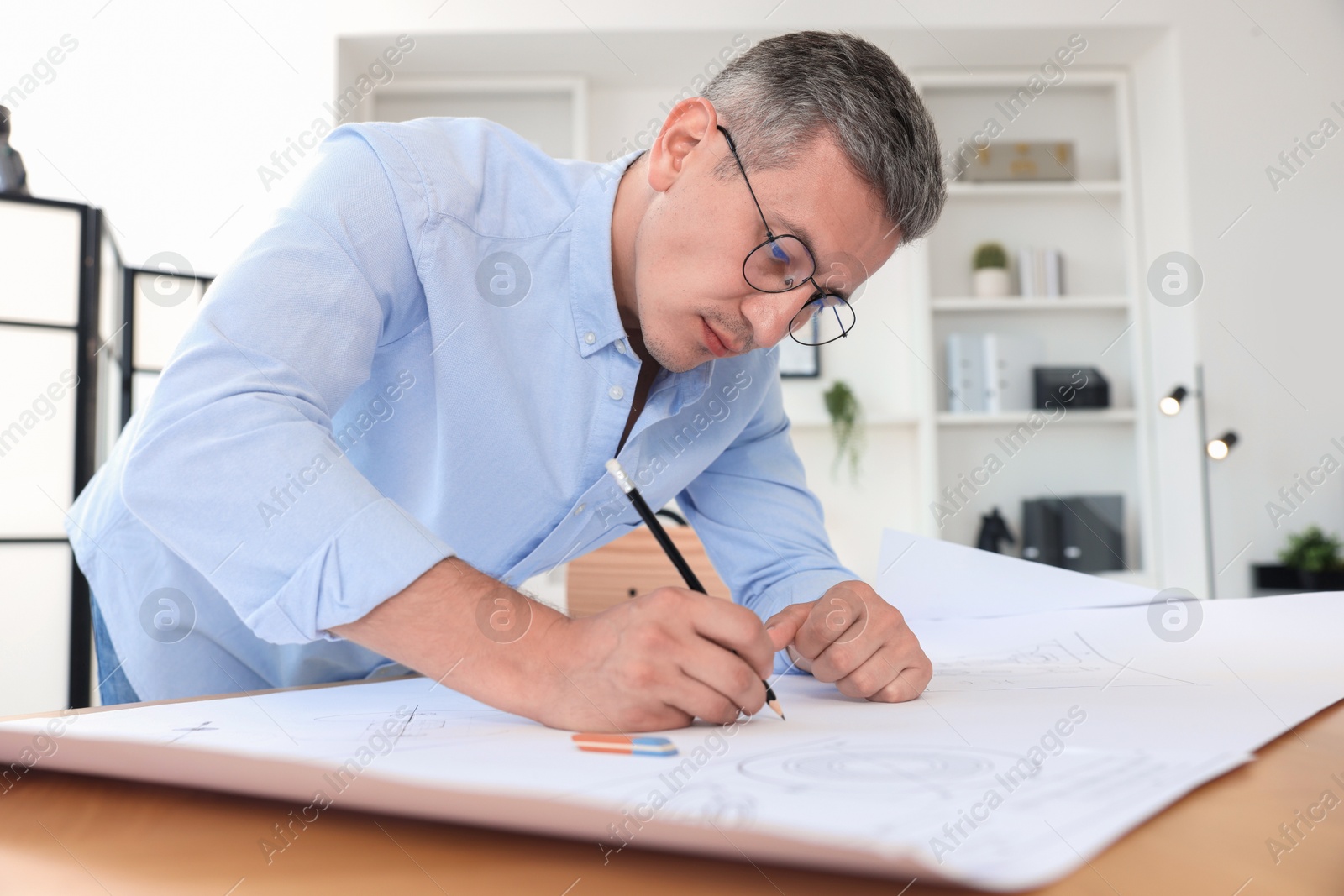 Photo of Architect making engineering drawing at wooden table in office