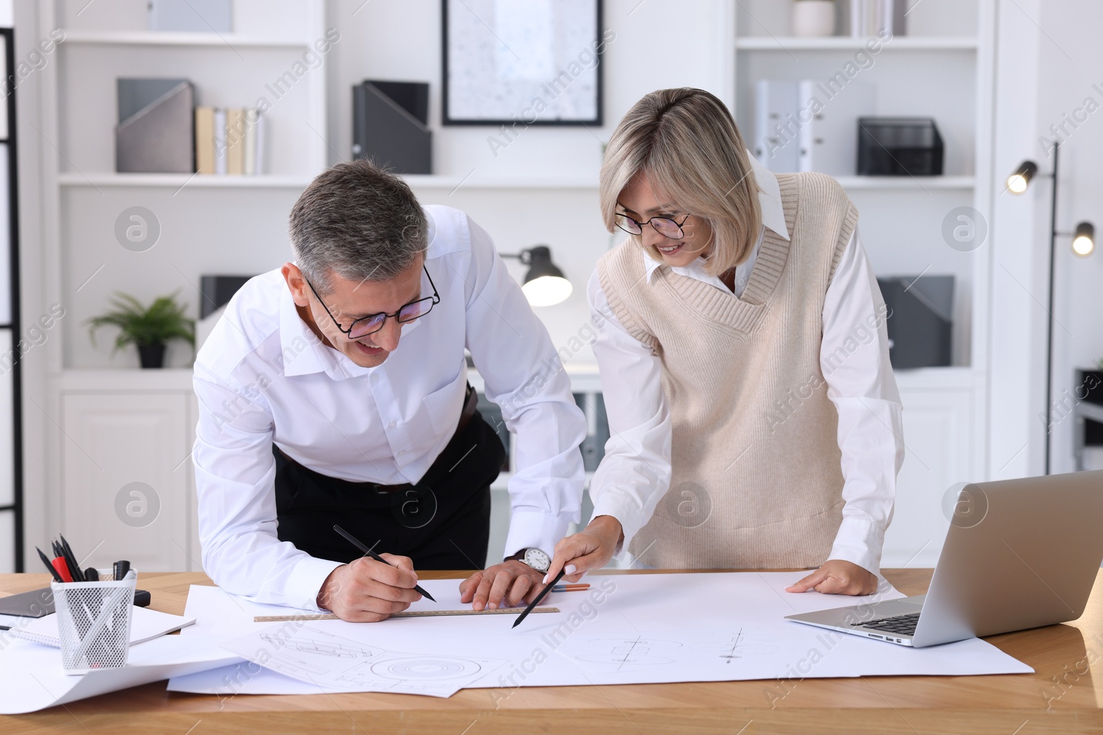 Photo of Architects making engineering drawing at wooden table in office