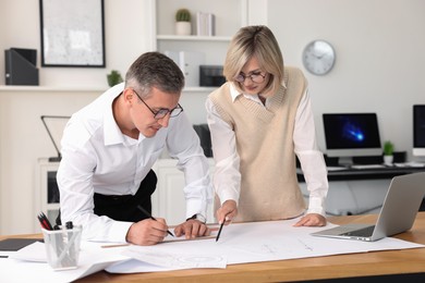 Architects making engineering drawing at wooden table in office