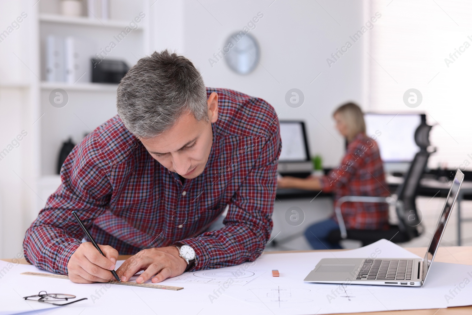 Photo of Architect making engineering drawing at table in office