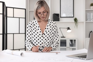 Photo of Architect making engineering drawing at table in office