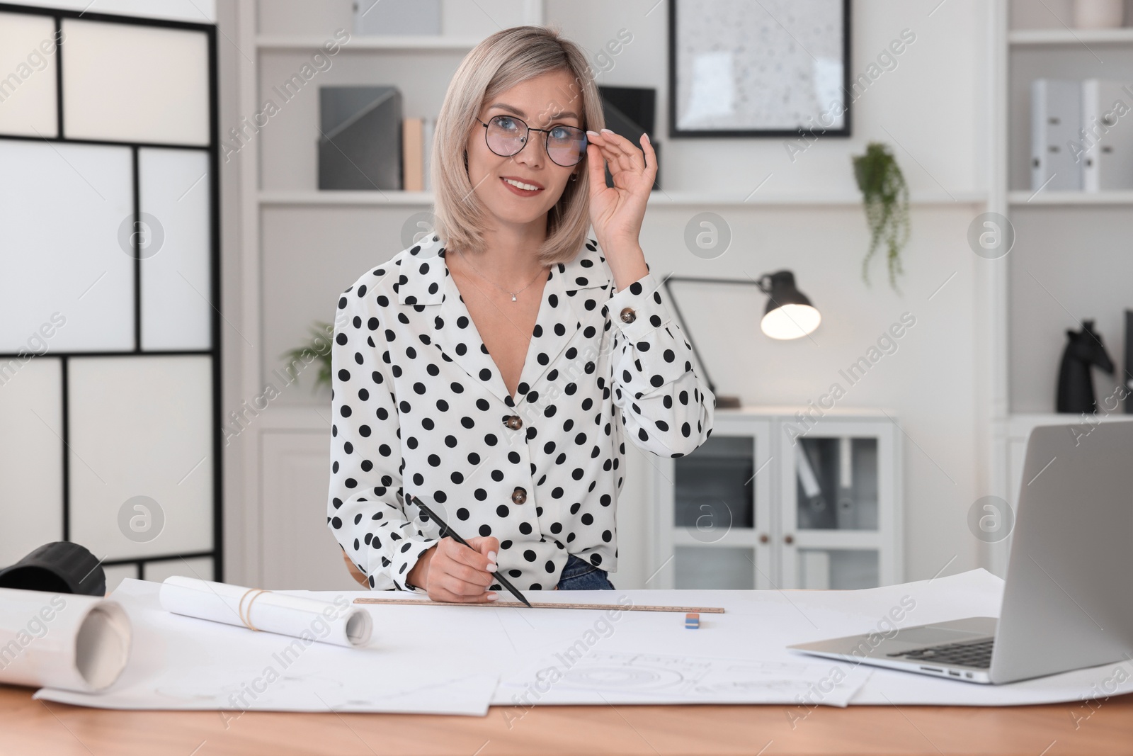 Photo of Architect making engineering drawing at wooden table in office