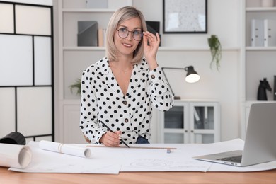 Architect making engineering drawing at wooden table in office