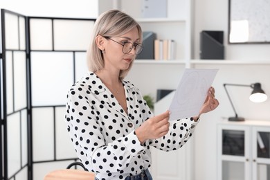 Architect holding paper sheet with engineering drawing in office