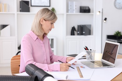 Architect making engineering drawing at table in office