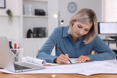 Architect making engineering drawing at table in office