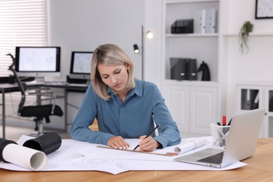 Photo of Architect making engineering drawing at table in office