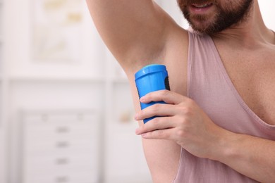 Photo of Man applying solid deodorant at home, closeup. Space for text