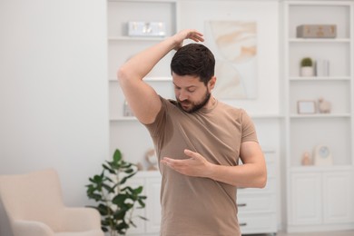 Photo of Emotional man in t-shirt before using deodorant at home