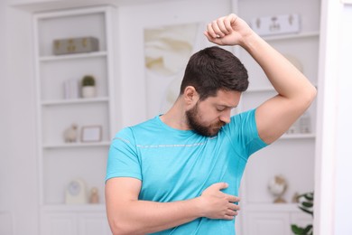 Emotional man in t-shirt before using deodorant at home