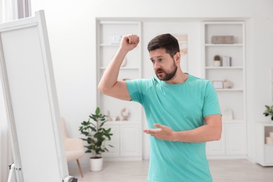 Photo of Emotional man in t-shirt before using deodorant at home