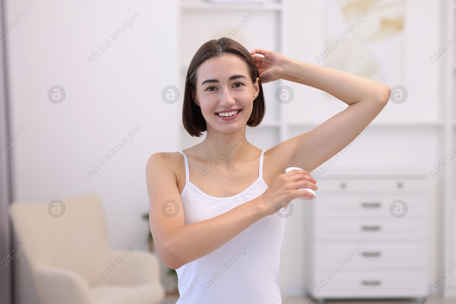 Photo of Smiling woman applying solid deodorant at home