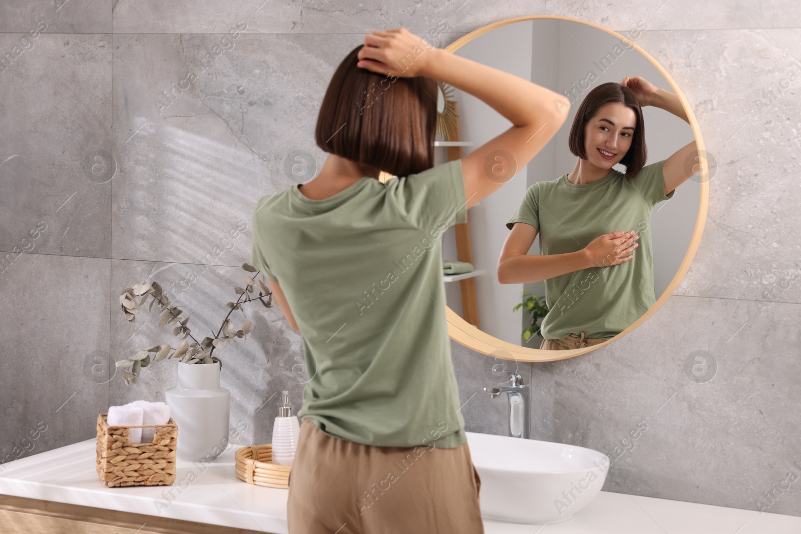 Photo of Smiling woman after using deodorant near mirror at home