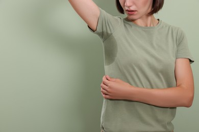 Woman before using deodorant on green background, closeup. Space for text