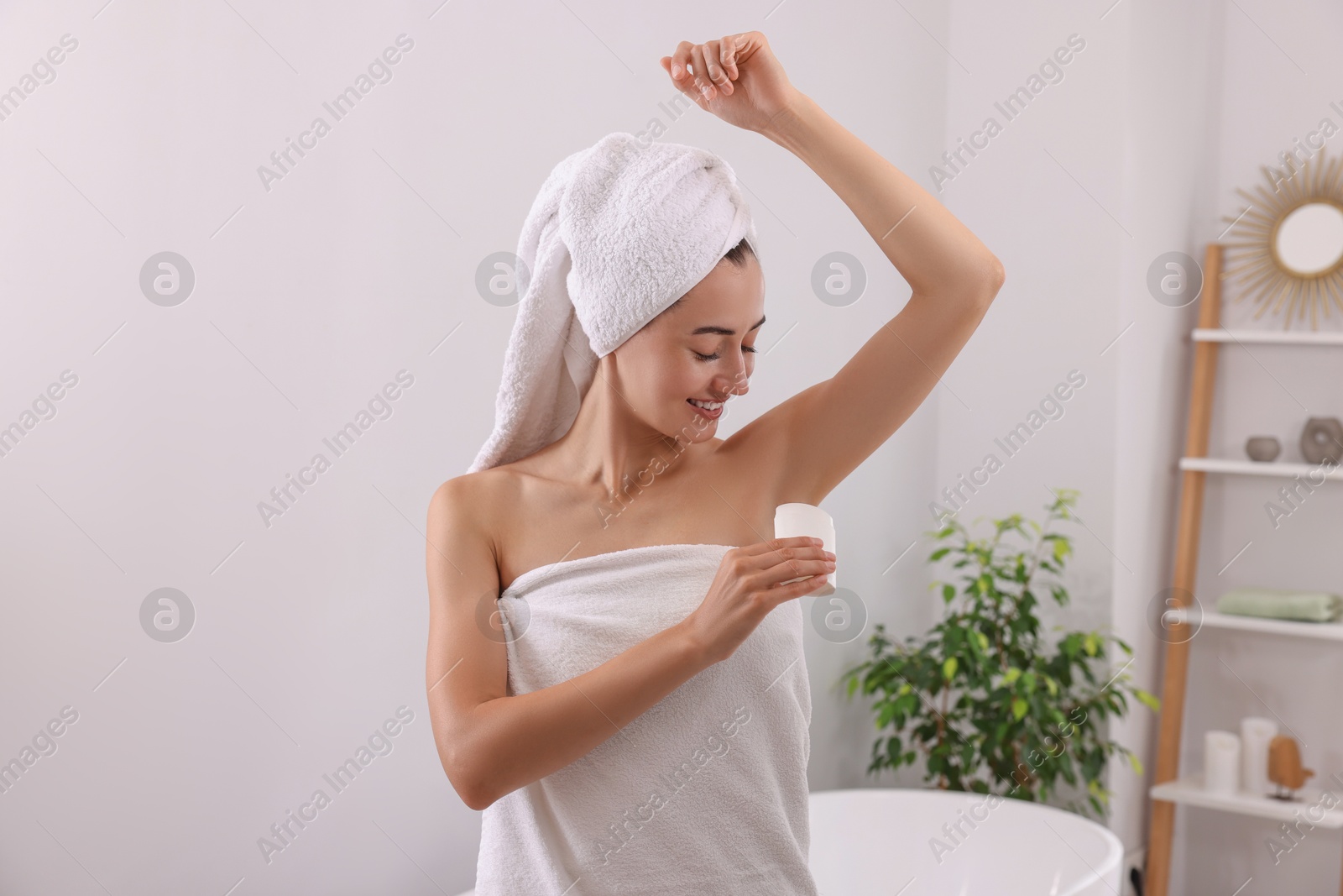 Photo of Smiling woman applying solid deodorant at home