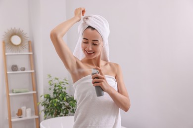 Photo of Smiling woman applying spray deodorant at home