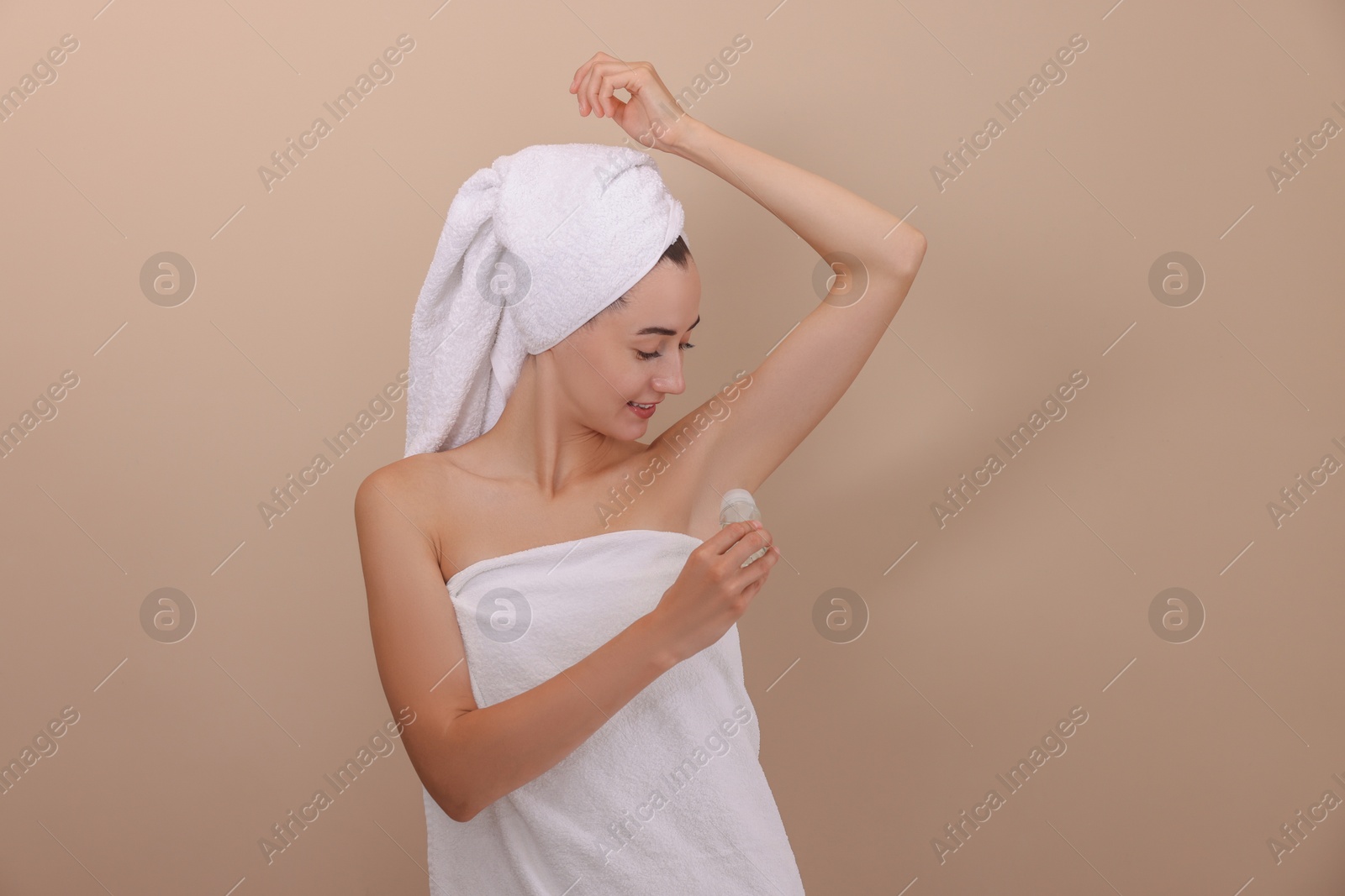 Photo of Smiling woman applying roll-on deodorant on beige background