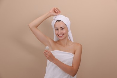 Photo of Smiling woman applying roll-on deodorant on beige background