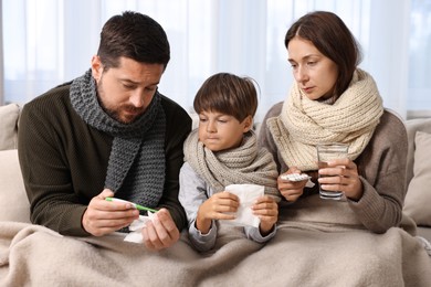 Cold symptom. Family suffering from fever on sofa at home