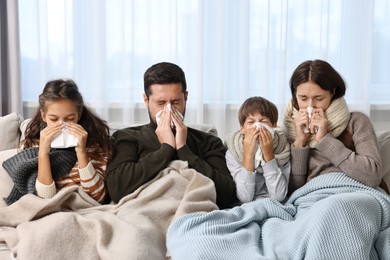 Cold symptom. Family suffering from fever on sofa at home