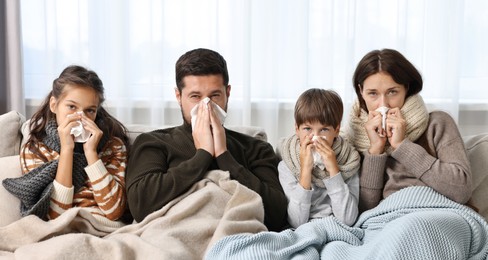 Photo of Cold symptom. Family suffering from fever on sofa at home