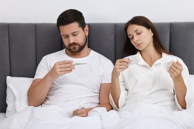 Photo of Cold symptom. Couple suffering from fever in bed at home