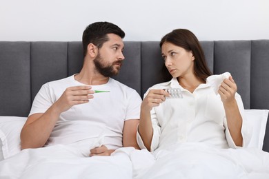 Cold symptom. Couple suffering from fever in bed at home