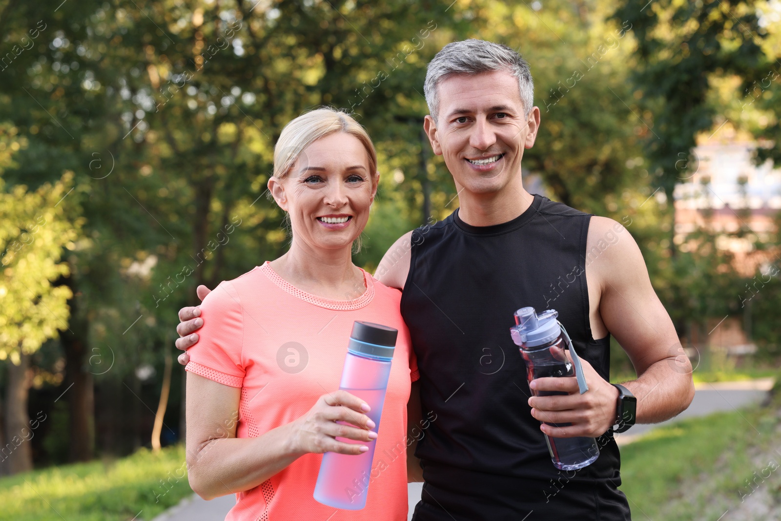 Photo of Happy couple with bottles of water in park