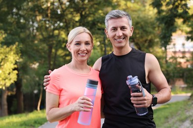 Happy couple with bottles of water in park