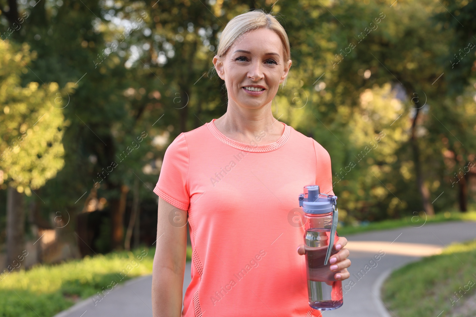 Photo of Happy woman with bottle of water in park