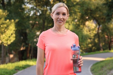 Happy woman with bottle of water in park