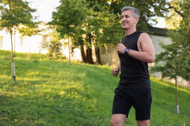 Smiling man running in park, space for text