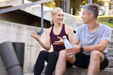 Photo of Smiling couple with bottle of water on steps outdoors