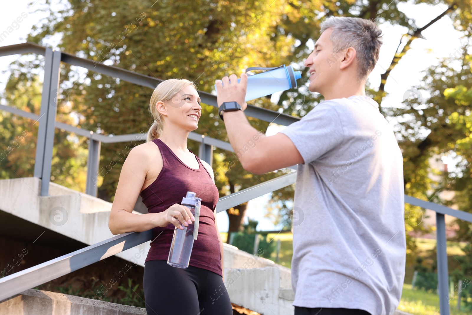 Photo of Happy couple with bottles of water in park