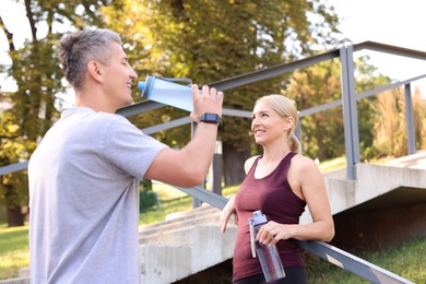 Photo of Happy couple with bottles of water in park