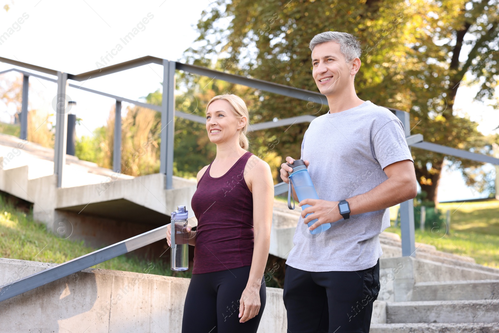 Photo of Happy couple with bottles of water in park