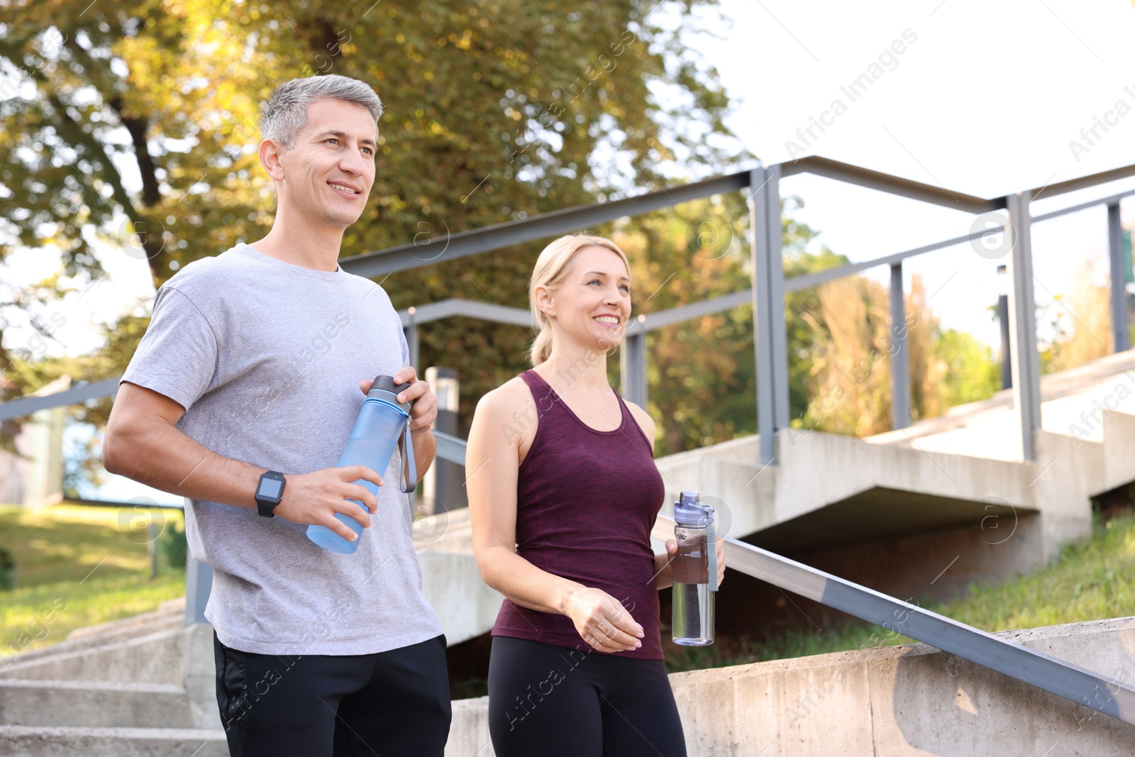 Photo of Happy couple with bottles of water in park