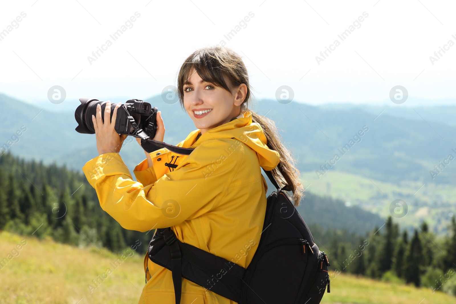 Photo of Photographer with backpack and camera taking picture of beautiful mountains