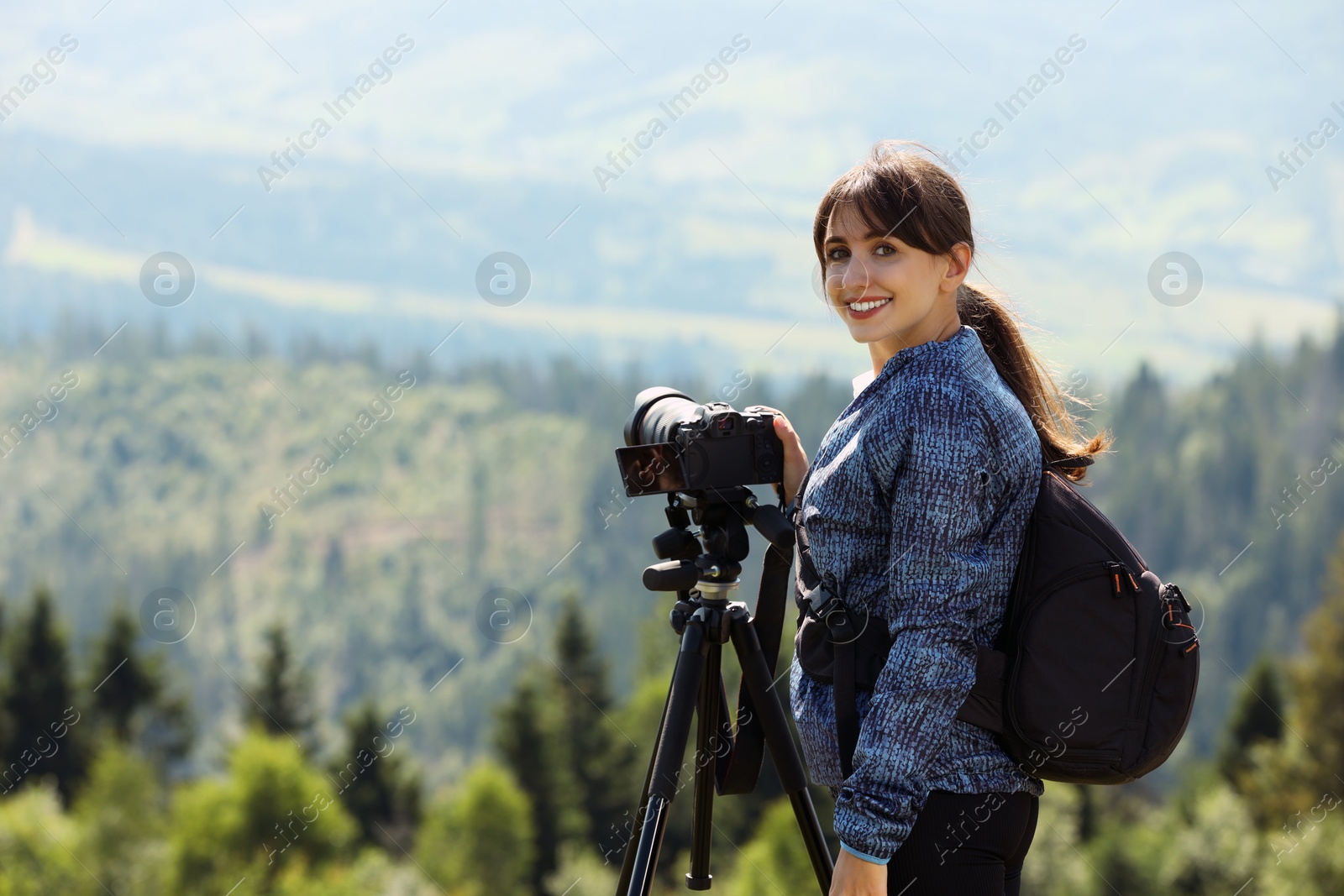 Photo of Photographer with backpack and camera on tripod taking picture of beautiful mountains. Space for text