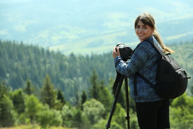 Photo of Photographer with backpack and camera on tripod taking picture of beautiful mountains. Space for text