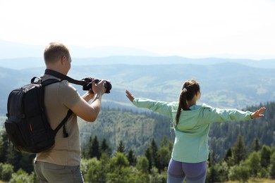 Photographer with backpack and camera taking picture of model in beautiful mountains