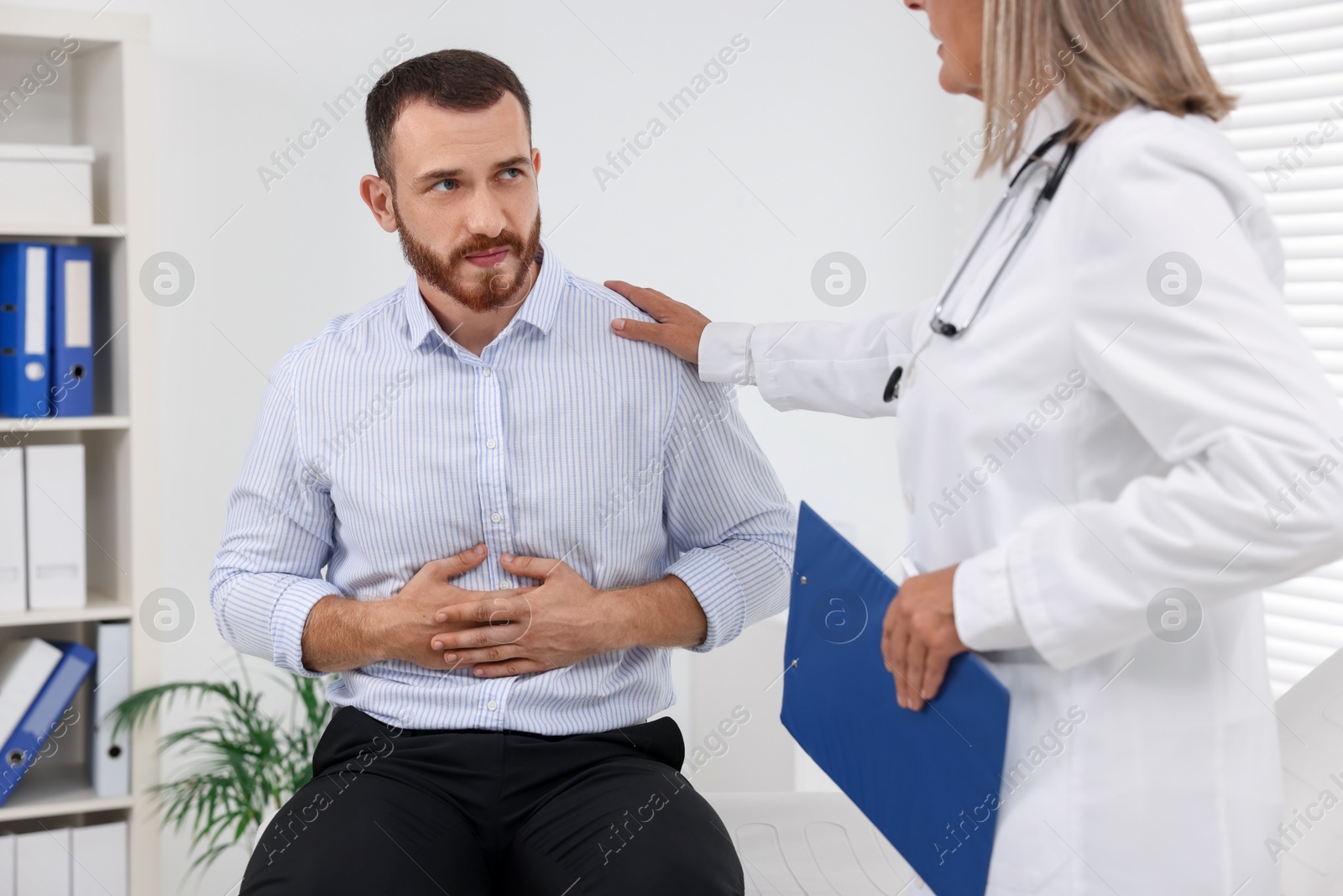 Photo of Doctor consulting patient with stomach pain in clinic, closeup